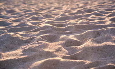Close up of clean yellow sand surface covering seaside beach illuminated with evening light. Travel and vacations concept