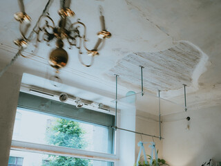 Vintage interior. Antique style white ceiling with wooden part. Glass hanging shelf. Swinging retro chandelier. Motion blur.