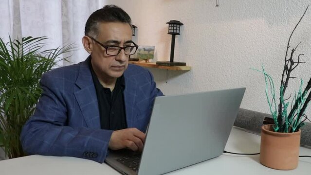 Hombre latino ejecutivo con anteojos trabajando en computadora