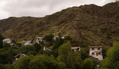 Panorama view of the old houses built along the hill and forest, under a cloudy sky. 