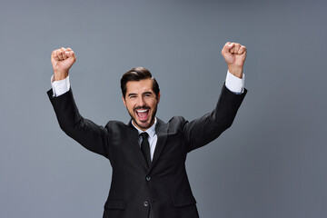 Business man happy smile with teeth open mouth raised hands up fists bump winner on gray background in business suit.