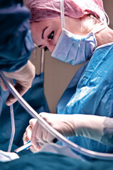 Surgeon and his assistant performing cosmetic surgery in hospital operating room. Surgeon in mask...