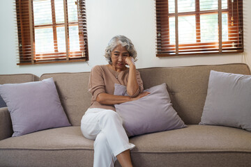 Portrait of a senior man thinking about something, feeling sad, sitting on sofa, asian people.