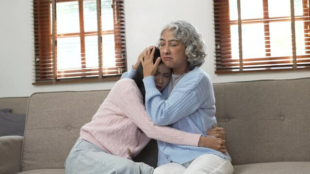 Asia mature woman mother with doughter sitting on sofa.
