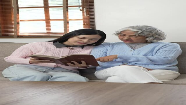 Old Mother And Daughter Reading Book, sitting on sofa.