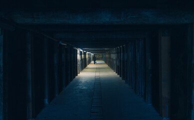 Dark corridor tunnel illuminated with timber and wooden pylons and beams.