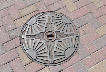 1930's art deco manhole cover in cobblestone road