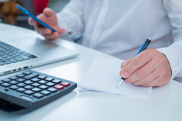 professional man uses calculator laptop and smartphone in office close up