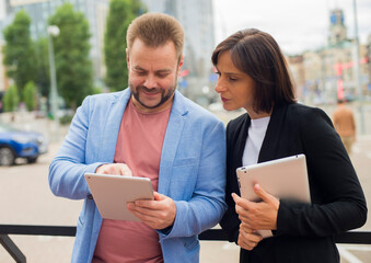 partners employees use a tablet on the street.professional man and woman on the background of the city with a tablet are discussing something.business project startup teamwork concept.