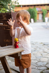 a baby boy plays with a nesting doll on a wooden table outside