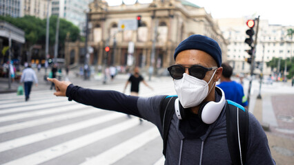 black man talks on cellphone and listens to music on an afternoon in the city