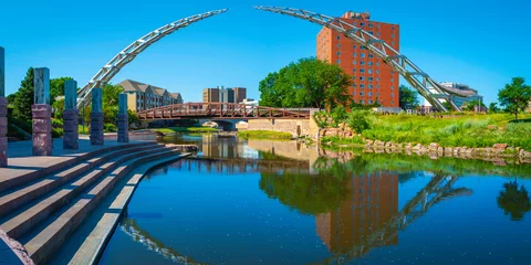 Zelfklevend Fotobehang Big Sioux River public park riverfront trail landscape with water reflections of the bridges in downtown Sioux Falls, South Dakota, USA © Naya Na