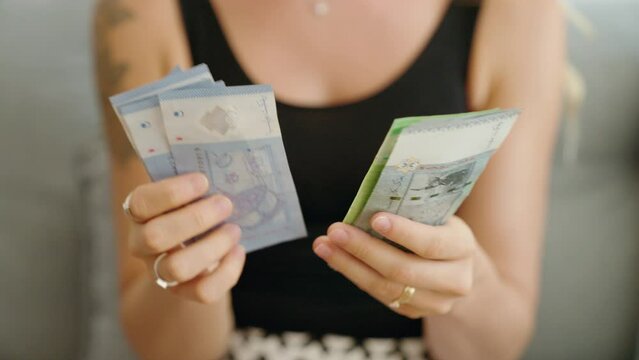 Young woman counting malaysia ringgit banknotes at home