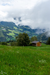 Obraz premium Landschafts Aufnahme einer Hütte umgeben von Bäumen und einer Wiese in den Bergen