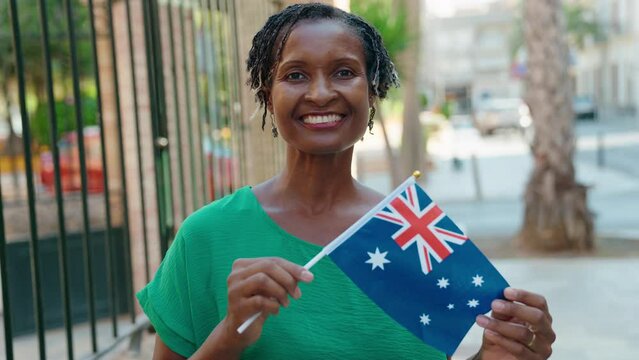 Middle age african american woman smiling confident holding australia flag at street