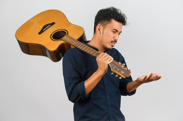 Portrait of Young Asian man carrying an acoustic guitar isolated on white background