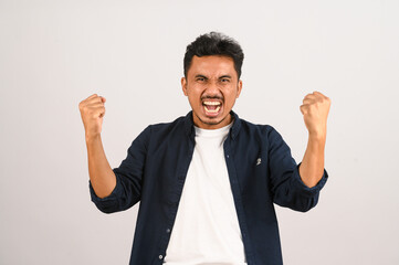 Portrait of Happy young asian man in blue shirt excited doing winner gesture with arm raised isolated on white background