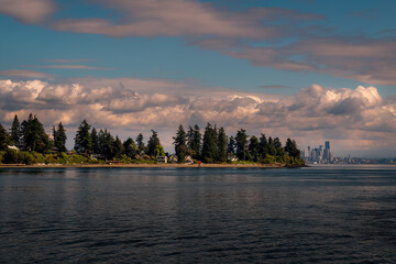 2022-11-11 BAINBRIDGE ISLAND SHORELINE WITH NICE CLOUDS AND PART OF THE SEATTEL SKYLINE IN THE...