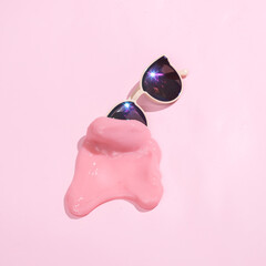 Creative minimalist layout. Sunglasses with slime on a pink background. Surreal summer idea. Conceptual pop