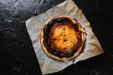 Freshly baked Basque cheesecake on parchment paper, on black slate