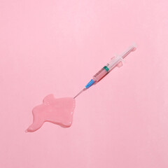 Creative medicine layout. Syringe with slime on a pink background. Surreal idea. Conceptual pop