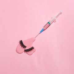 Creative layout. Syringe with false eyelashes and slime on a pink background. Beauty concept. Conceptual pop