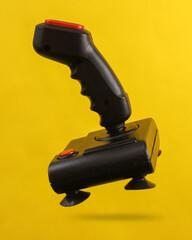 Retro joystick levitating on a yellow background with a shadow
