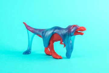 Toy dinosaur tyrannosaurus rex with slime on a turquoise background. Minimalism creative layout