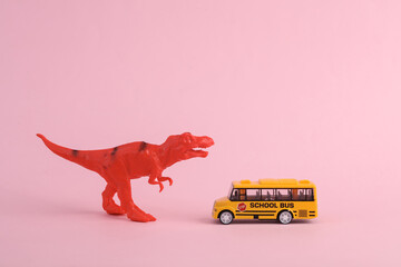 Toy two dinosaur tyrannosaurus rex with school bus on pink background. Minimalism creative layout