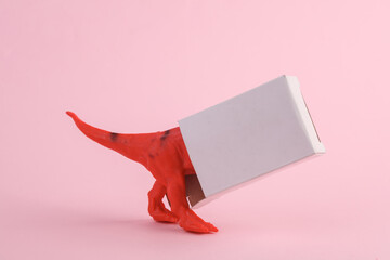 Toy two dinosaur tyrannosaurus rex with box on pink background. Minimalism creative layout