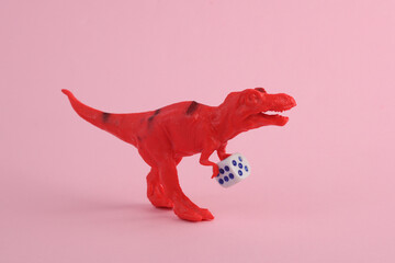 Toy dinosaur tyrannosaurus rex with dice on pink background. Minimalism creative layout