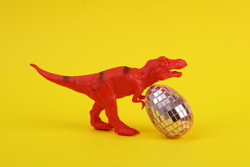 Toy dinosaur tyrannosaurus rex with mirror eggs on yellow background. Minimalism creative layout