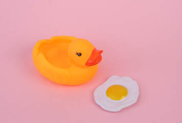 Rubber duck with scrambled eggs on a pink background. Creative layout