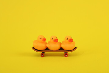 Rubber ducks ride on skateboard, pink background