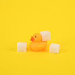 Rubber duck with sugar cubes on a yellow background