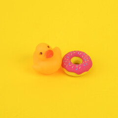 Rubber duck with donut on yellow background. Ninimalism creative layout