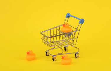 Rubber ducks with shopping trolley on yellow background. Ninimalism creative layout