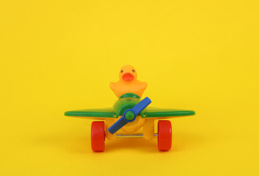 Rubber duck in toy airplane on a yellow background