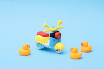 Toy scooter and rubber ducks on a blue background