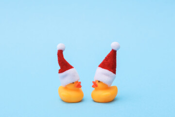 Two rubber ducks in a santa hat on a blue background. Christmas concept