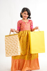 Happy Indian little girl holding shopping bags on white background.