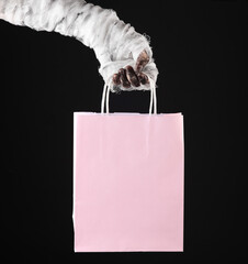 Mummy hand holding shopping bag isolated on black background. Halloween concept