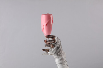 Mummy's hand wrapped in bandage holds glass with slime isolated on gray background. Halloween...