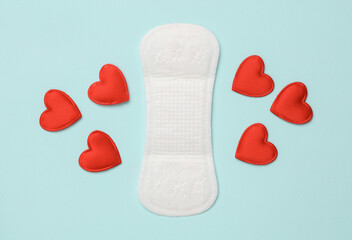 Pad with hearts on blue background. Feminine intimate hygiene concept