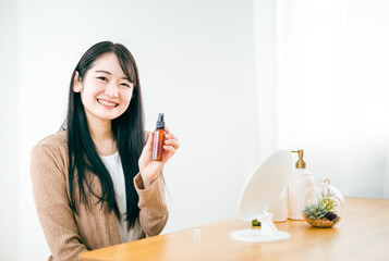 化粧品・コスメ・ヘアケア用品を持つ笑顔の日本人女性
