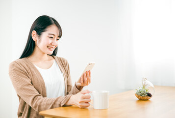 家でスマホのアプリを笑顔で使う日本人女性
