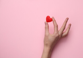 Female hand with heart on pink background. Valentine's day concept