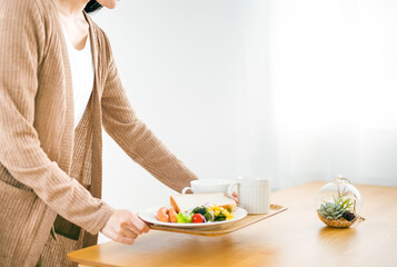 朝食をテーブルに運ぶ日本人女性
