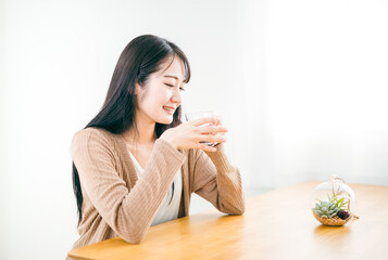 朝起床して水・白湯を飲んで温活する女性（笑顔）
