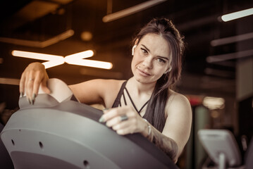 Fototapeta na wymiar Young attractive woman looking at camera while doing cardio on treadmill